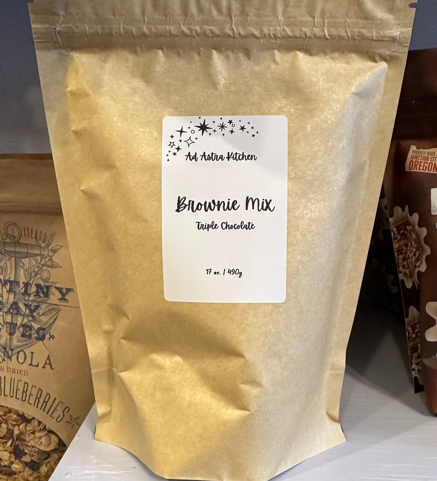 Bag of brownie mix with a label on a shelf with other food products.