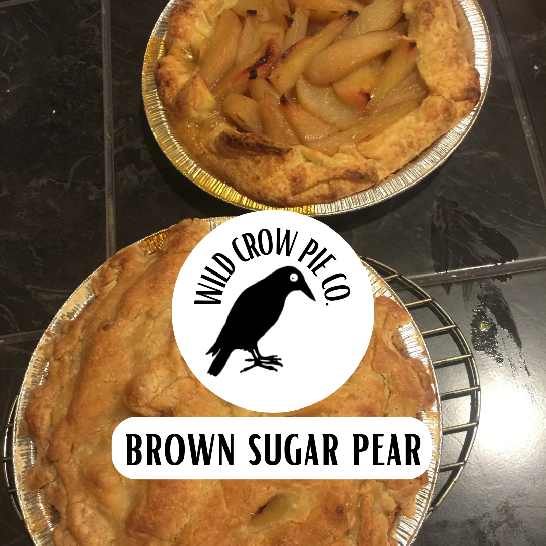 Two Brown Sugar Pear Pies on a black tile background, with the Wild Crow Pie Co. logo on a white circle