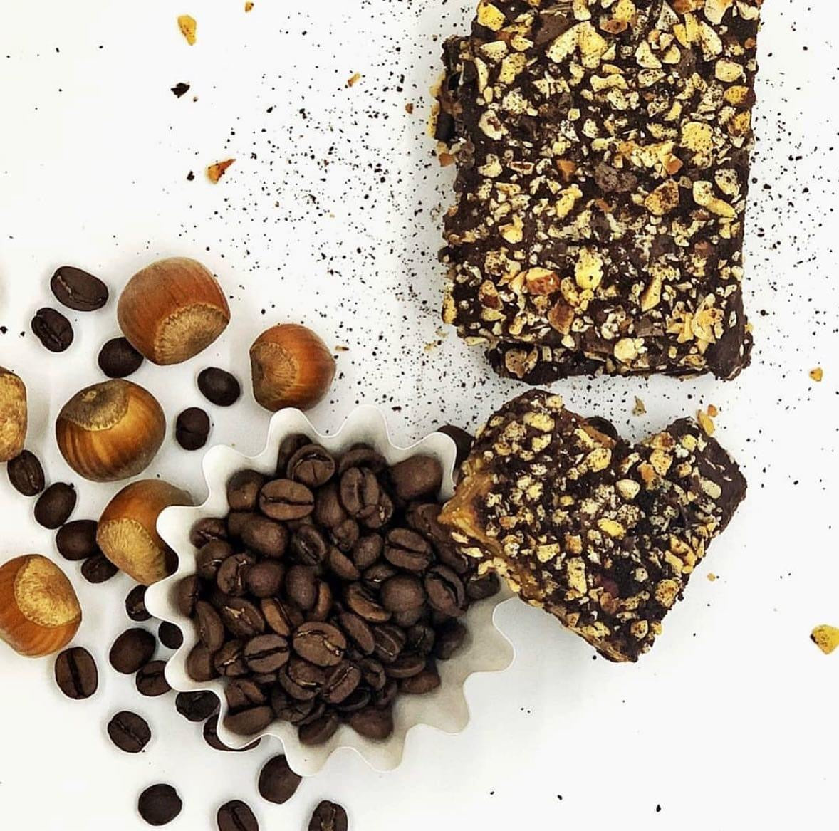 Toffee bars covered with dark chocolate and hazelnuts, alongside Oregon-grown hazelnuts and coffee beans.