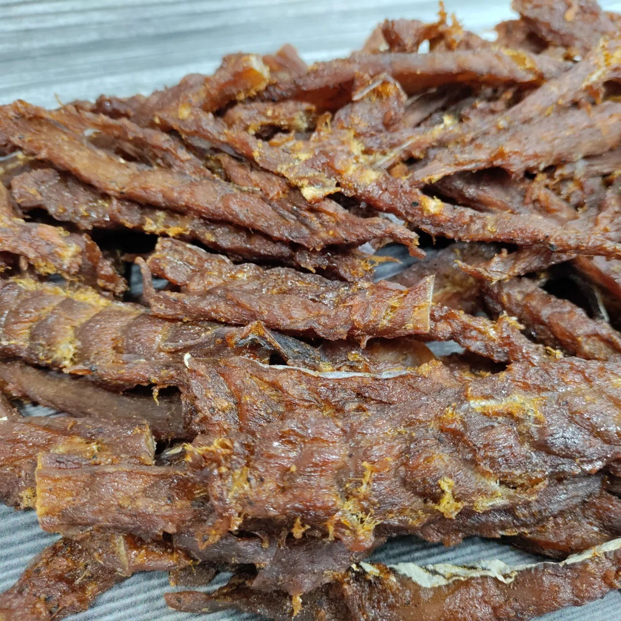 Dried cod fish jerky pieces on a gray surface