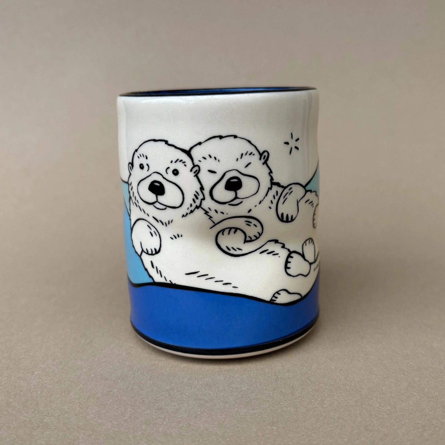 Ceramic mug with cartoon otters design on a beige background