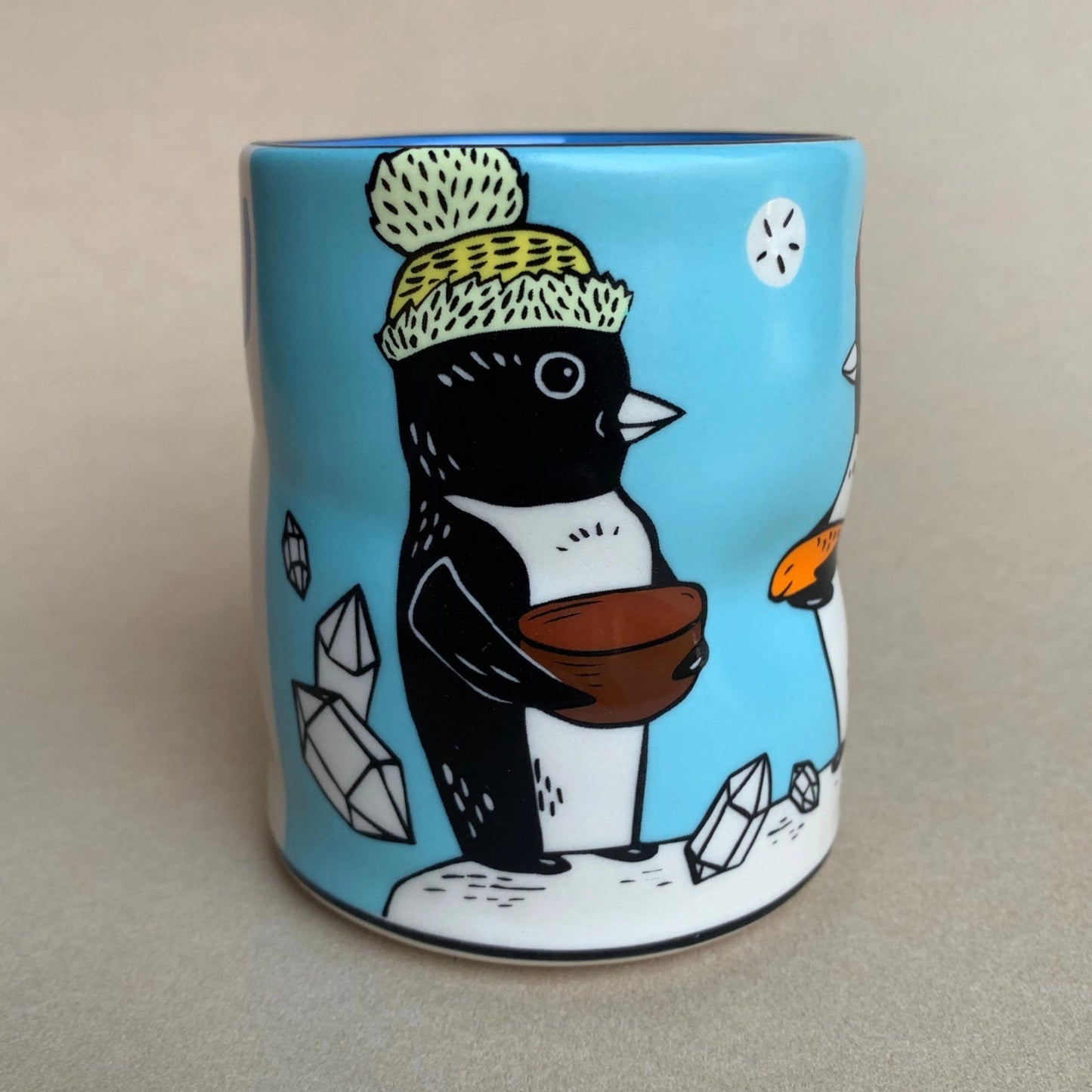 Mug with a penguin design holding a brown bowl on a light gray background