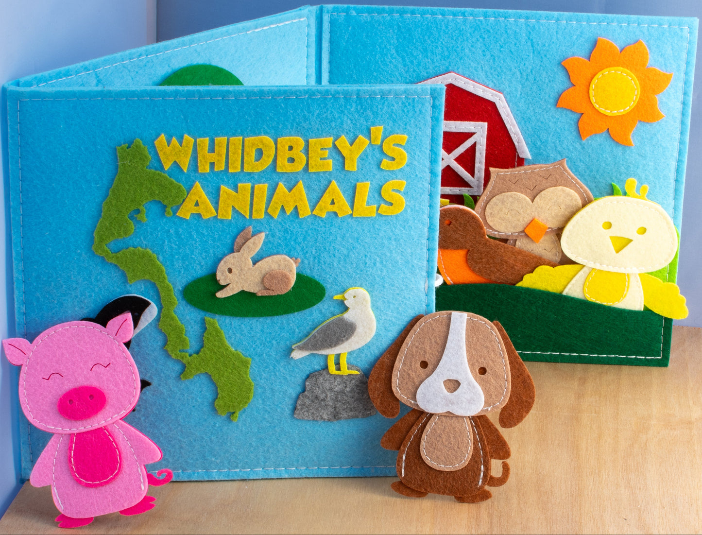 A colorful handcrafted felt book titled 'Whidbey's Animals' with various animal characters depicted in vibrant colors.