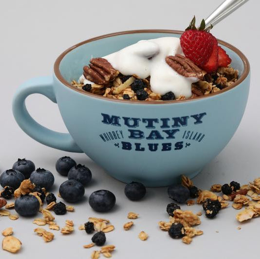 Granola with yogurt on it in a blue cup that says Mutiny Bay Blues