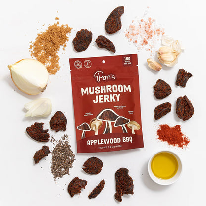 Pan's Mushroom Jerky Applewood BBQ package surrounded by ingredients on a white background