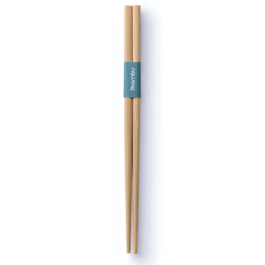 Two light brown rounded chopsticks held together  in the upper half with a dark green piece of paper, on white background