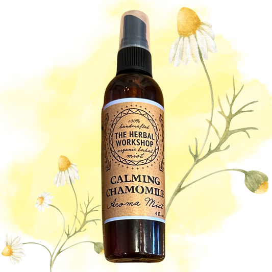 Bottle of 'Calming Chamomile Aroma Mist' from The Herbal Workshop with chamomile flowers in the background.