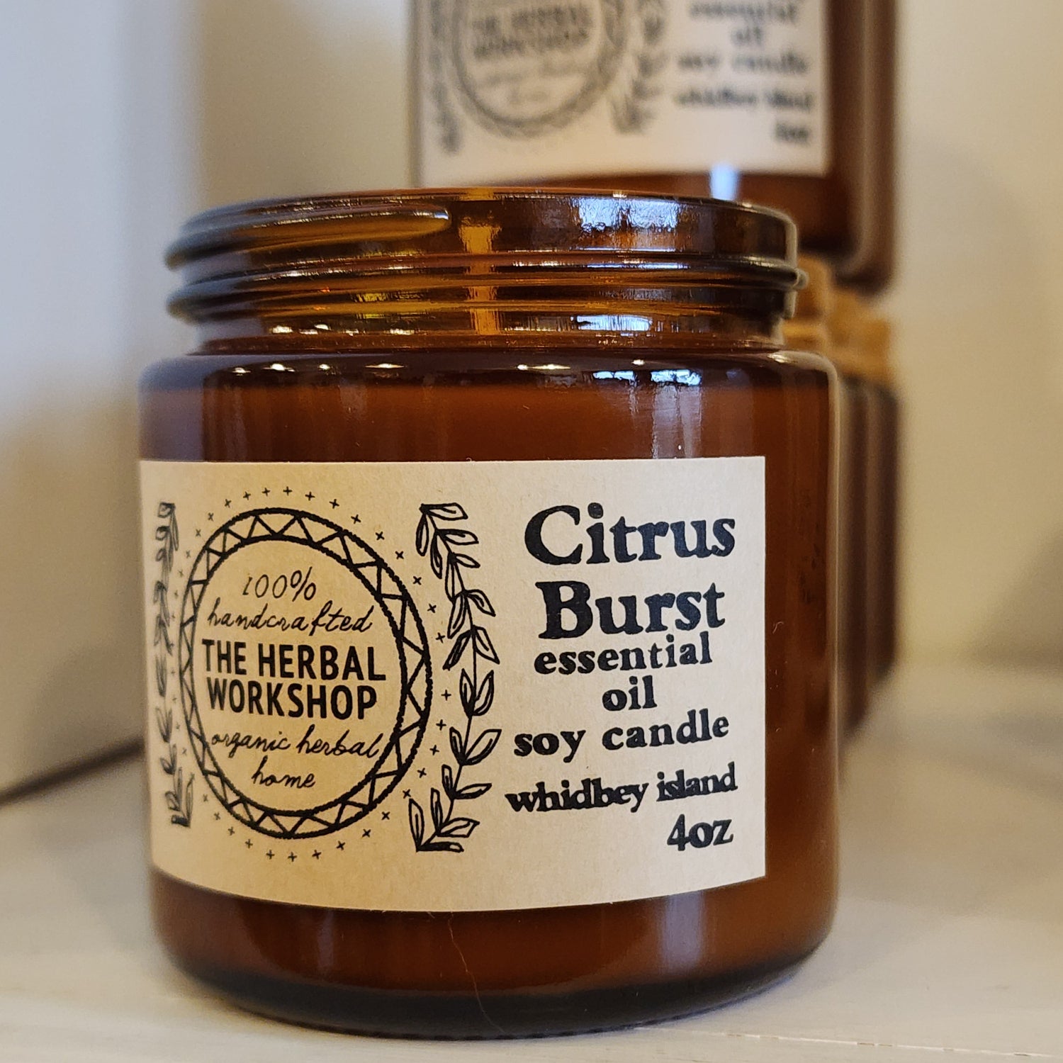 Amber glass candle jar with 'Citrus Burst' label on a blurred background