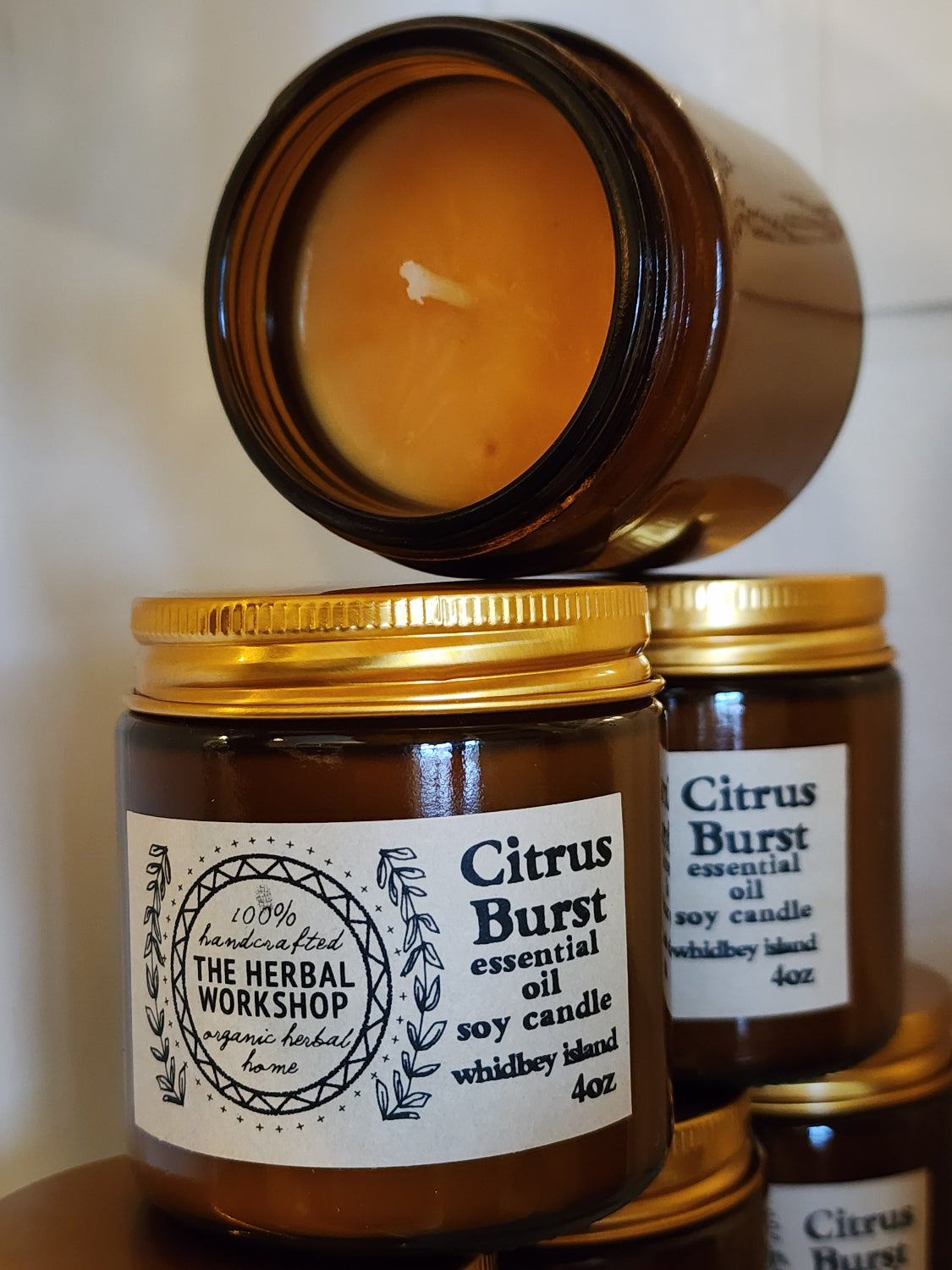 Brown candle jar with gold lid and label on a white background that says "Citrus Burst essential oil soy candle whidbey island 4oz"