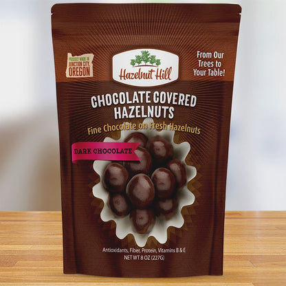 Packaging of Hazelnut Hill dark chocolate covered hazelnuts, featuring the product name, image of the hazelnuts, and additional product details.