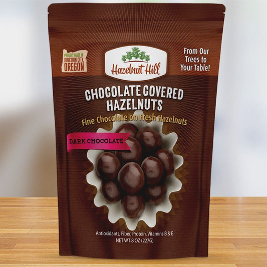Packaging of Hazelnut Hill dark chocolate covered hazelnuts, featuring the product name, image of the hazelnuts, and additional product details.