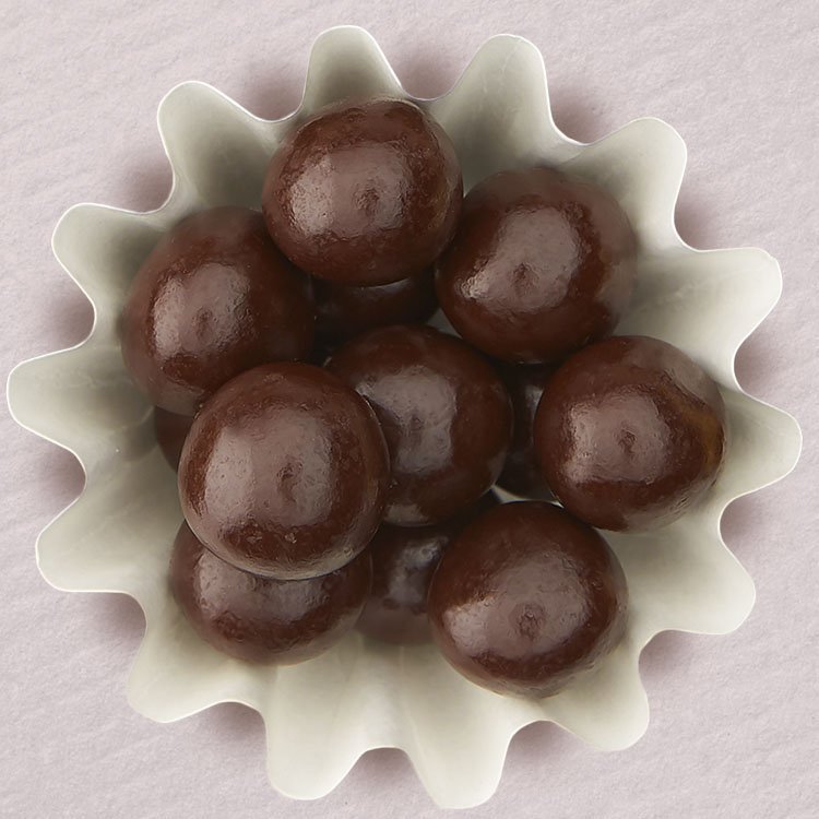 Dark chocolate covered hazelnuts in white cup