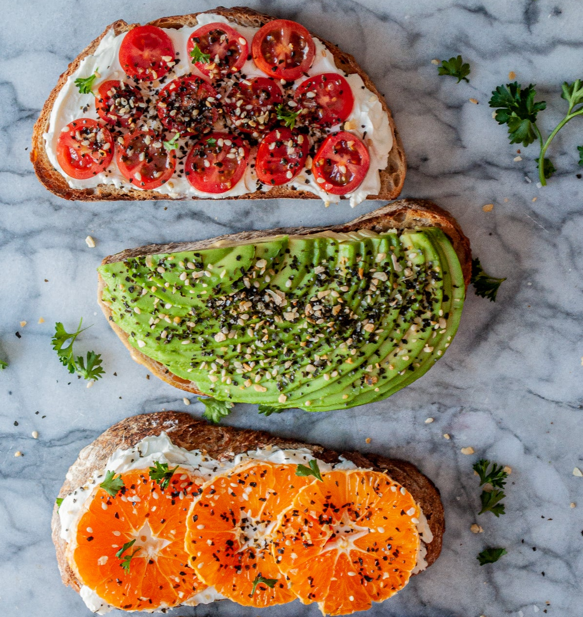 Four slices of toast with different toppings on a marble surface