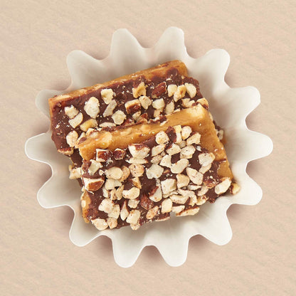 A small batch of hazelnut toffee made with Oregon-grown hazelnuts and dark chocolate, presented on a white plate.