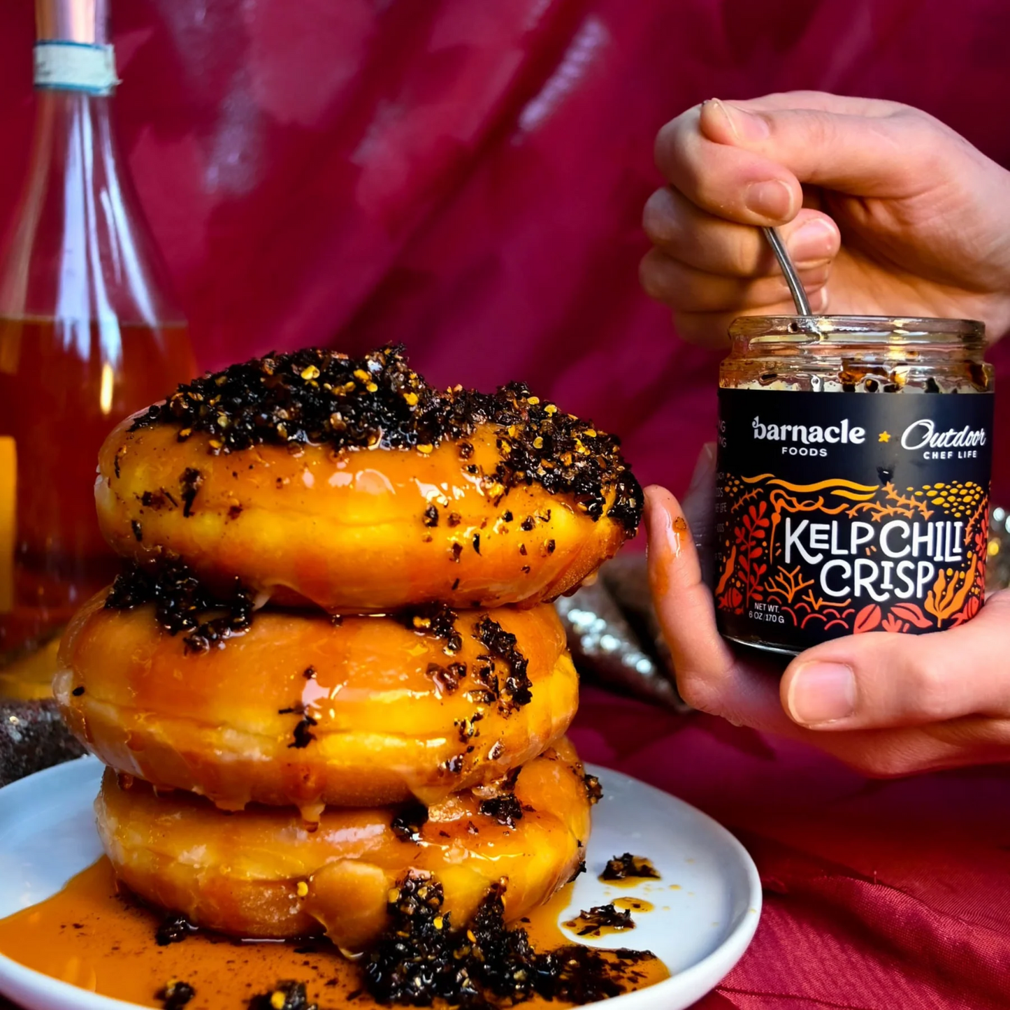 Stack of donuts with a jar of KelpChill Crisp seasoning on a red background
