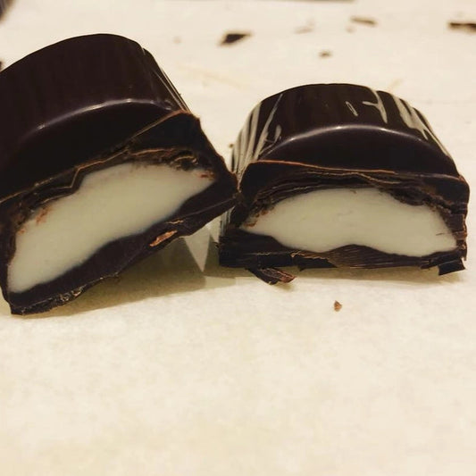 A dark chocolate bar cut in half to show a white mint creamy filling