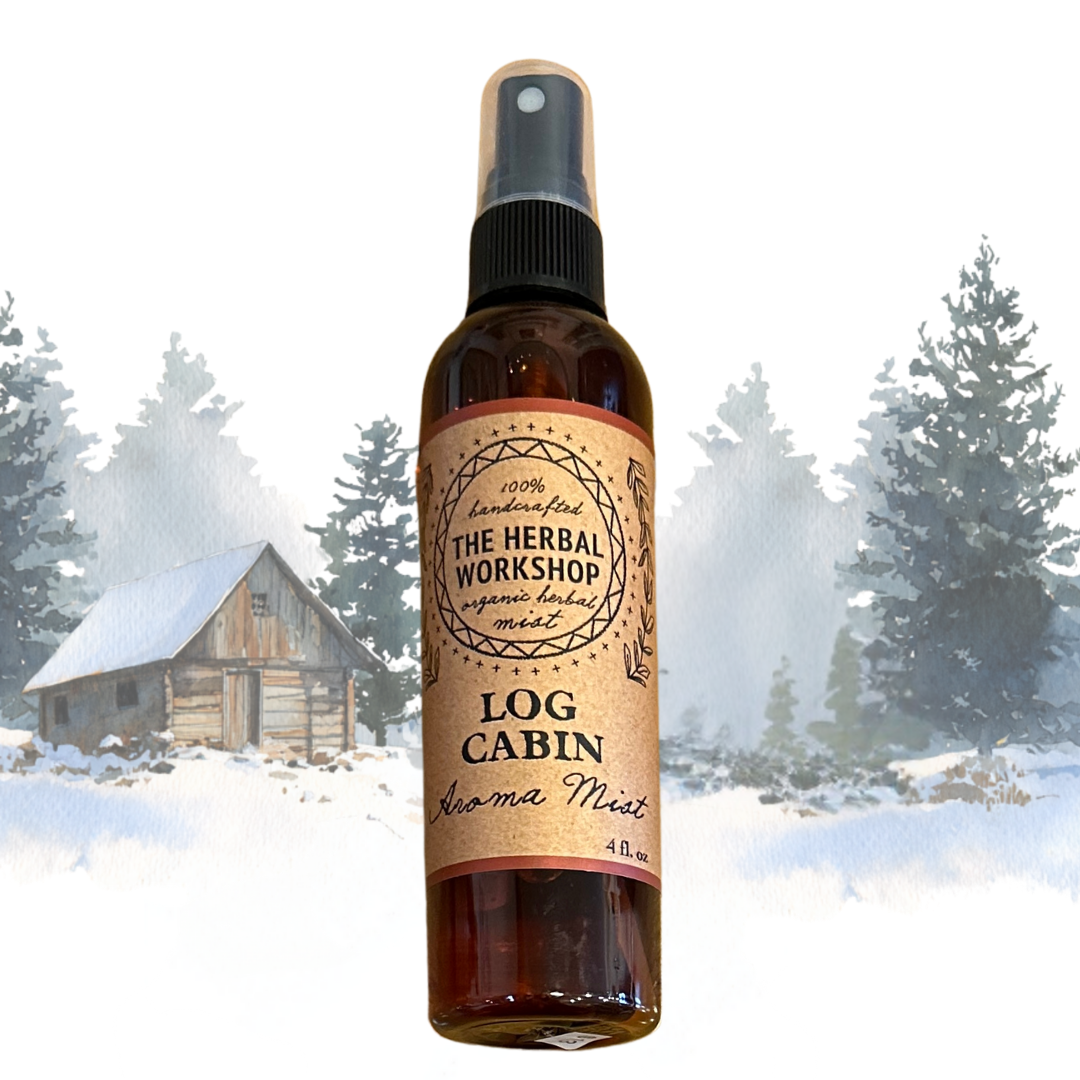 Bottle of 'Log Cabin' aroma mist from The Herbal Workshop with a snowy cabin and trees in the background.