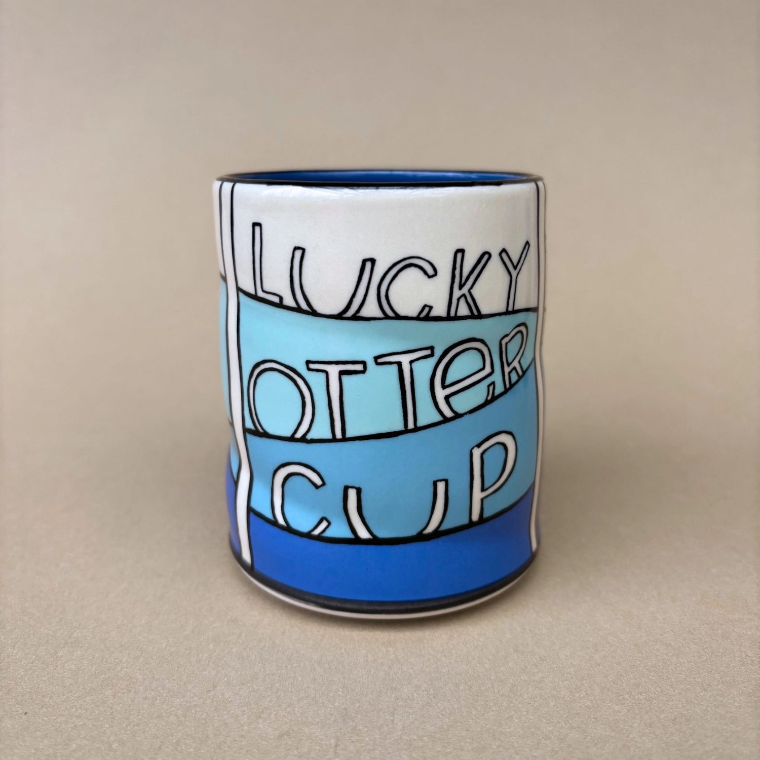Ceramic mug with 'Lucky Otter Cup' text on a beige background