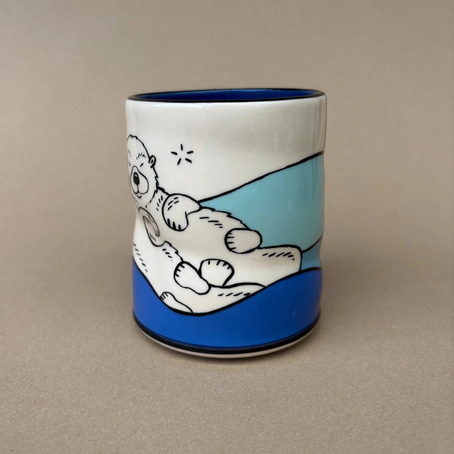Ceramic mug with an otter illustration on a beige background