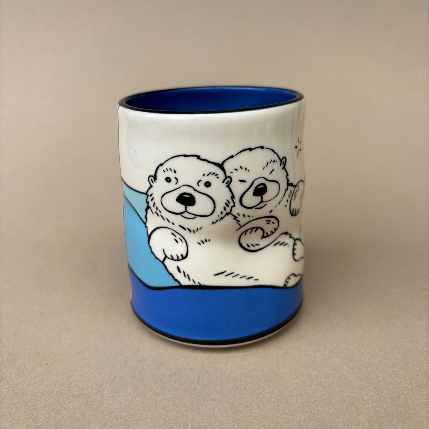 Ceramic mug with otter design on a beige background