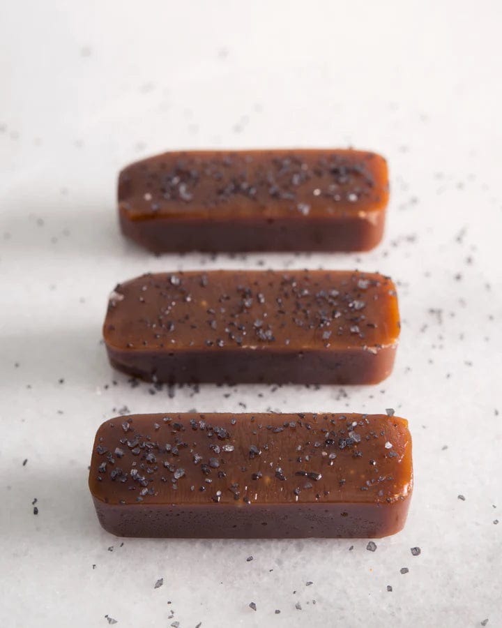 Three rectangular brown candies with specks on a light gray background