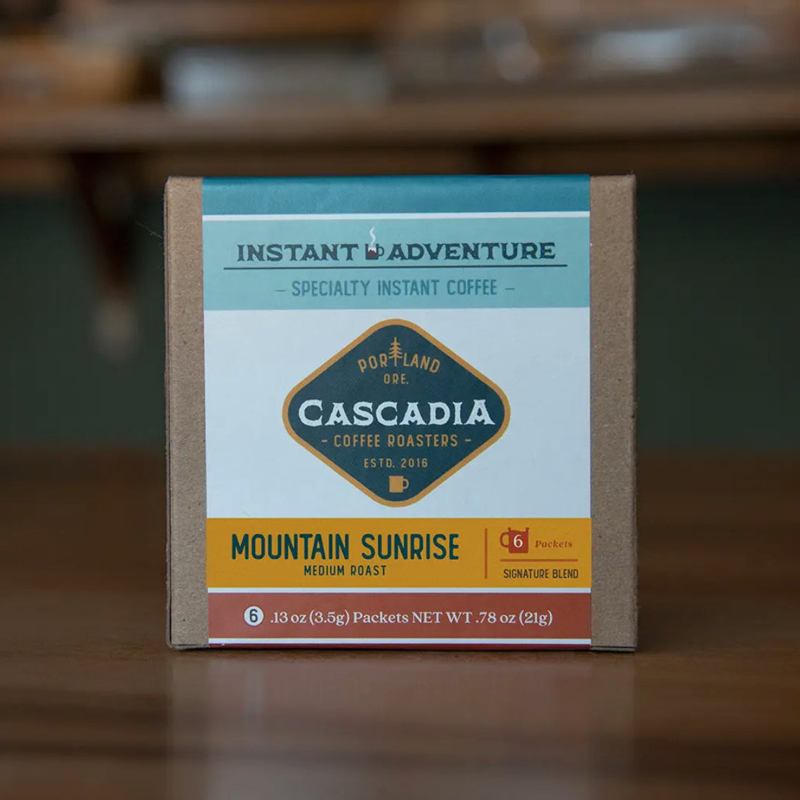 Box of Cascadia Coffee Roasters Instant Adventure Specialty Instant Coffee on a wooden surface.