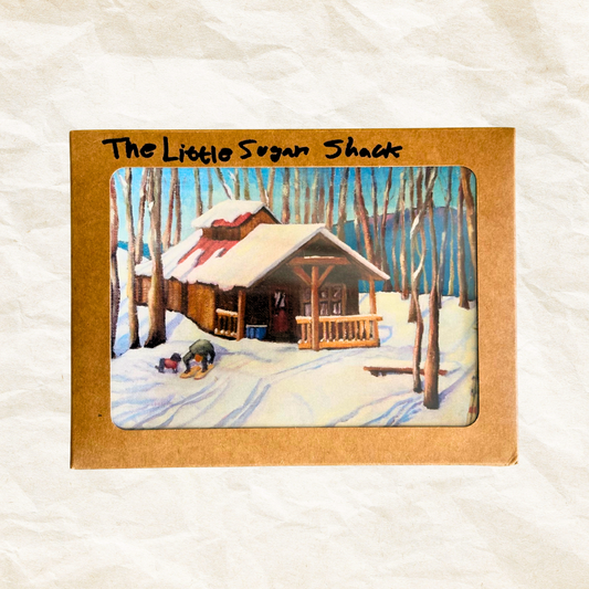 Card with a winter scene of a cabin labeled 'The Little Sugar Shack' on a textured white background.