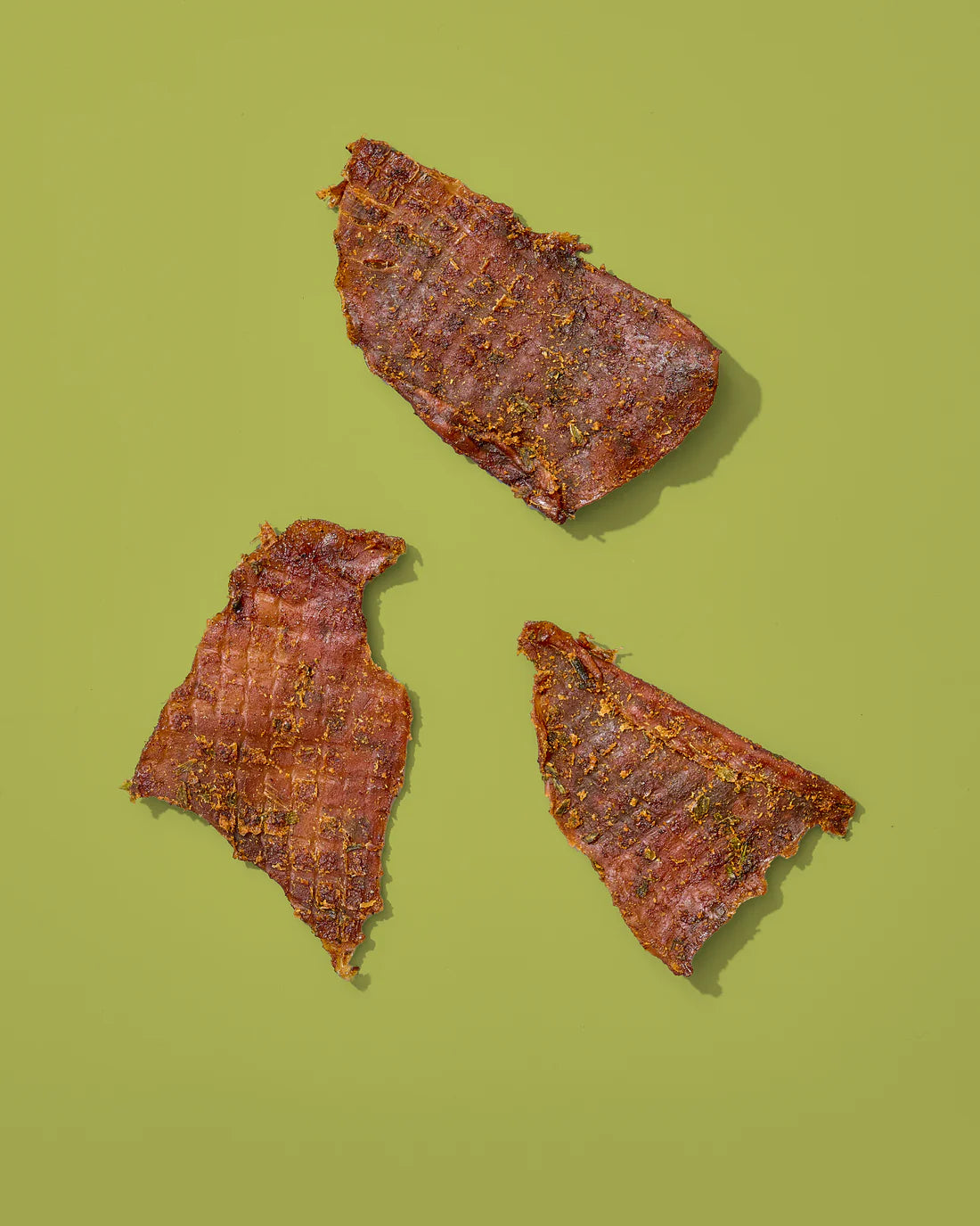 Three pieces of dried calamari on a green background