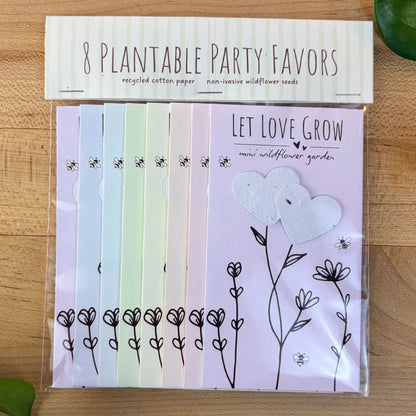 Pack of 8 plantable party favors with seed paper designs on a wooden surface.