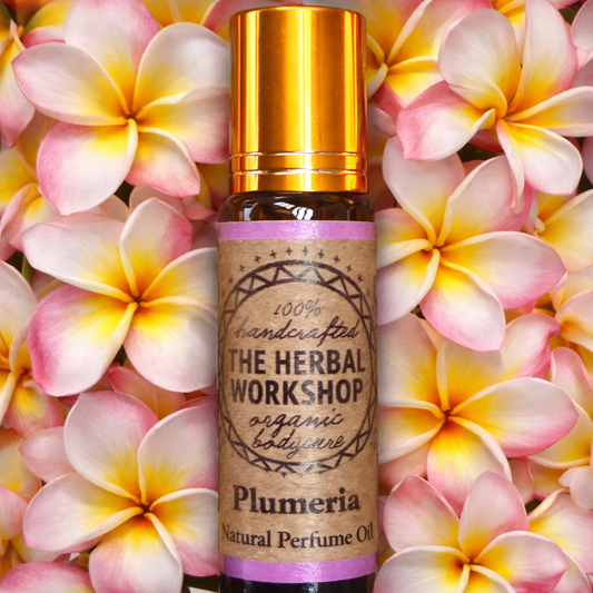 Bottle of The Herbal Workshop Plumeria natural perfume oil on a background of plumeria flowers.