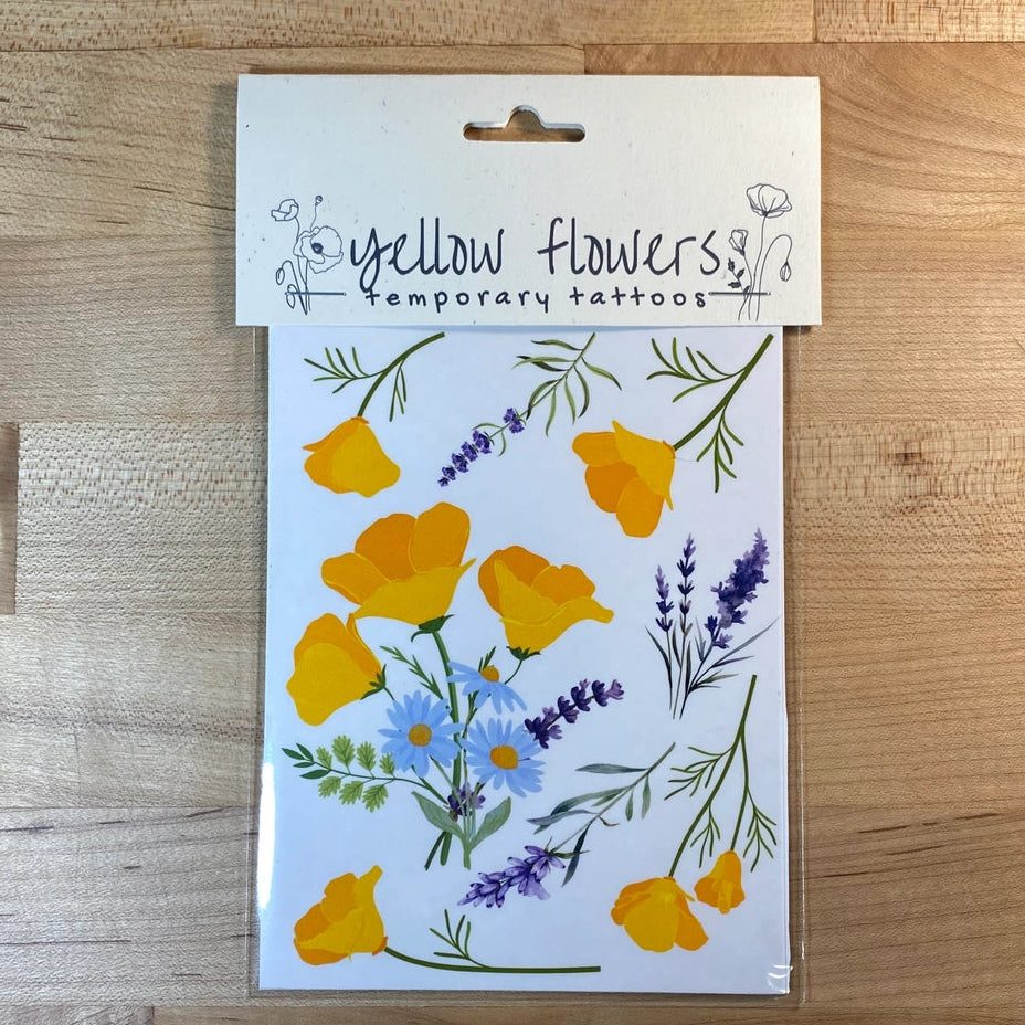 Pack of yellow flower temporary tattoos on a wooden surface