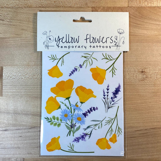 Pack of yellow flower temporary tattoos on a wooden surface