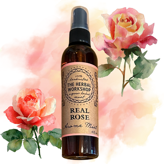 Bottle of 'Real Rose' aroma mist from The Herbal Workshop with roses in the background