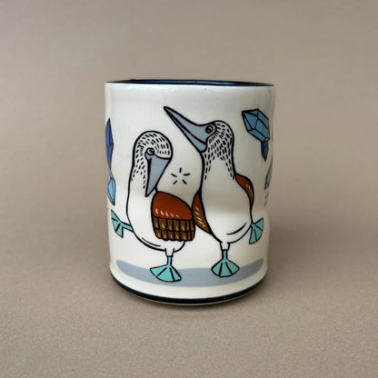 Ceramic mug with bird design on a beige background