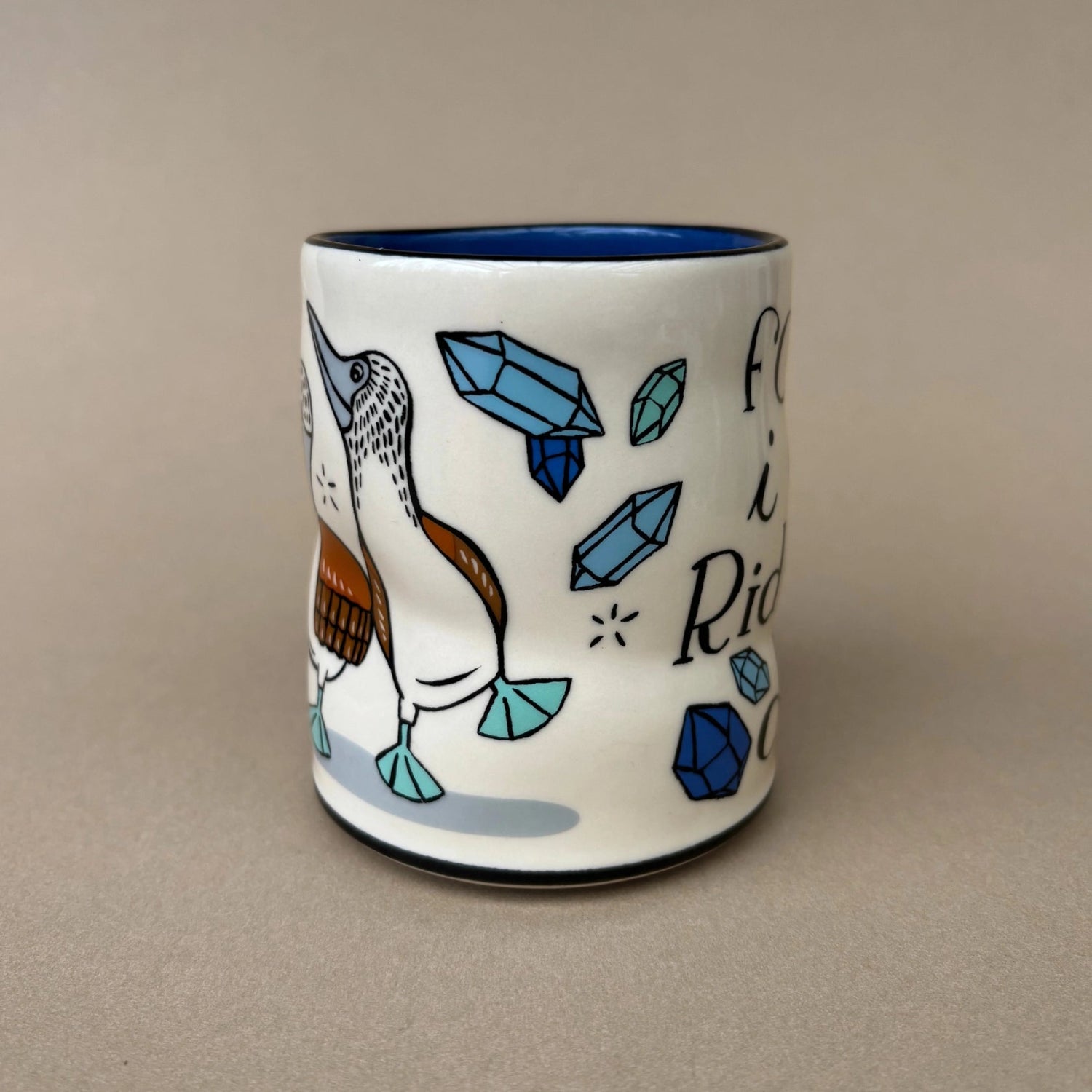 Ceramic mug with a bird design and blue accents on a beige background