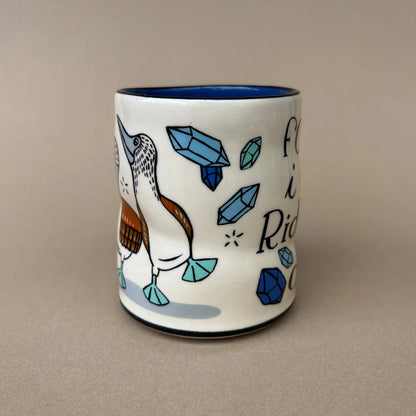 Ceramic mug with a bird design and blue accents on a beige background