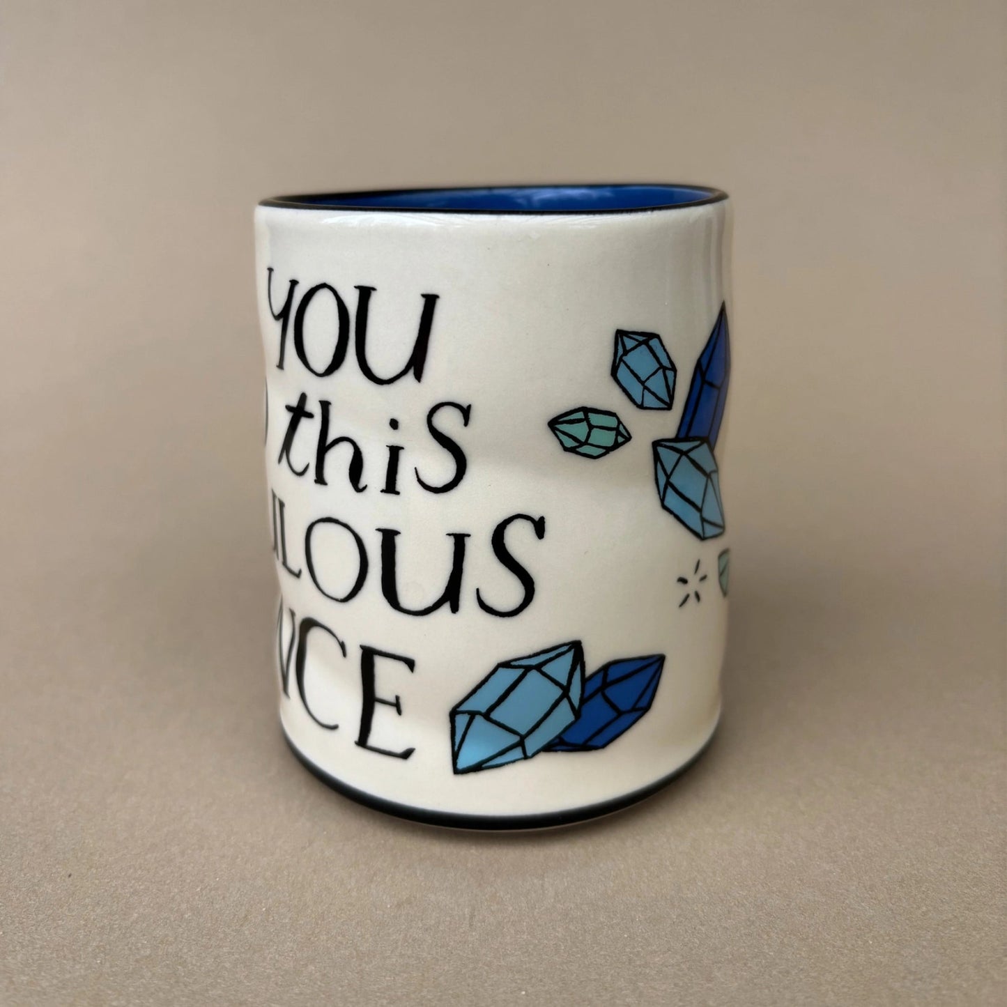 Ceramic mug with blue crystals and text on a beige background