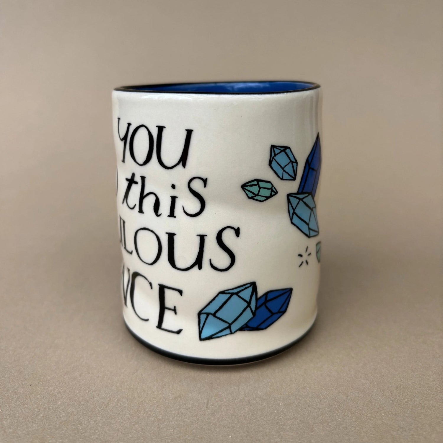 Ceramic mug with blue crystals and text on a beige background