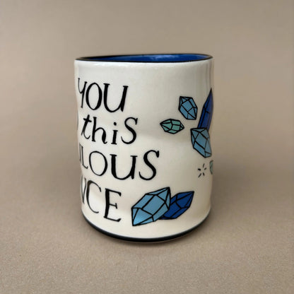 Ceramic mug with blue crystals and text on a beige background