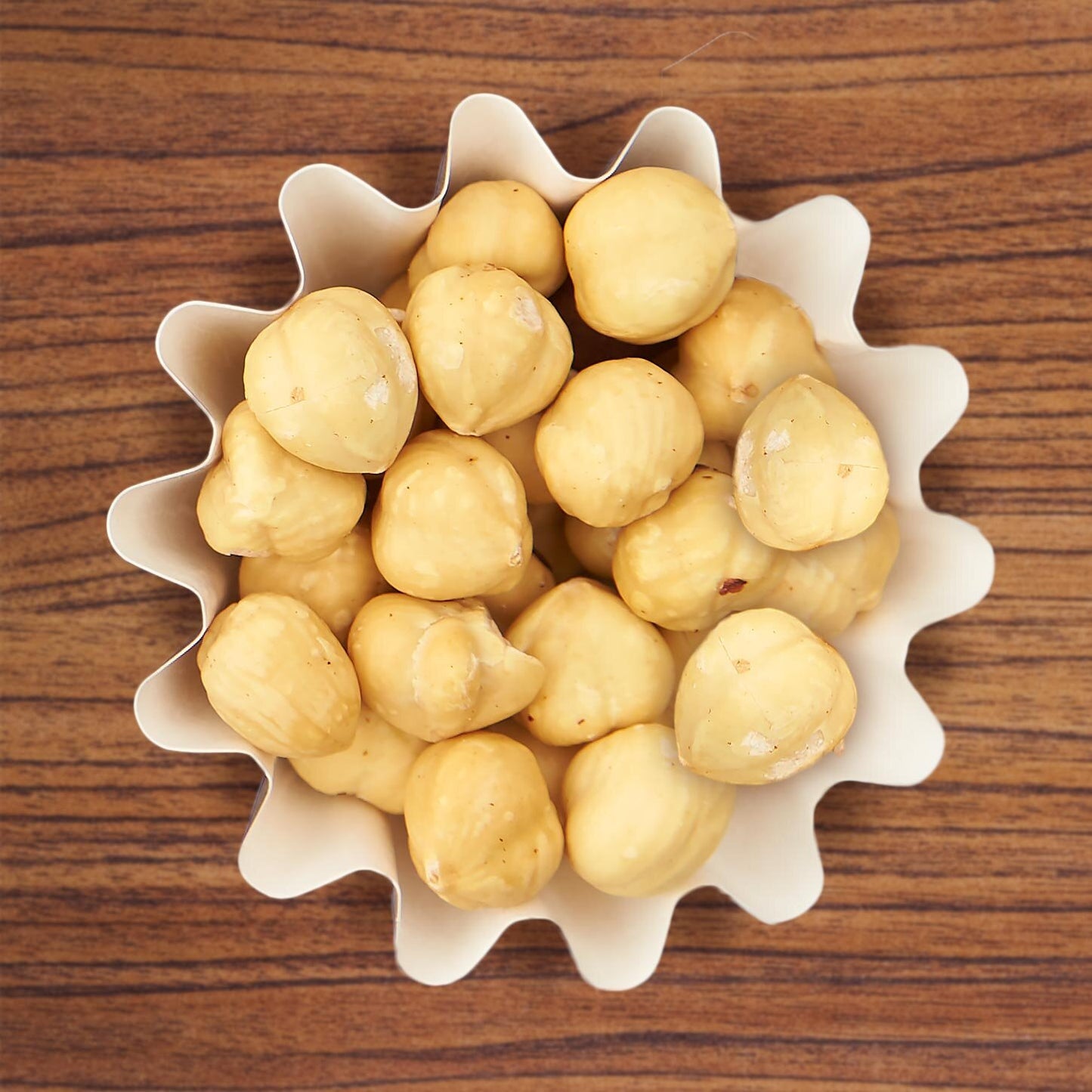 Roasted hazelnuts in white cup on wood background