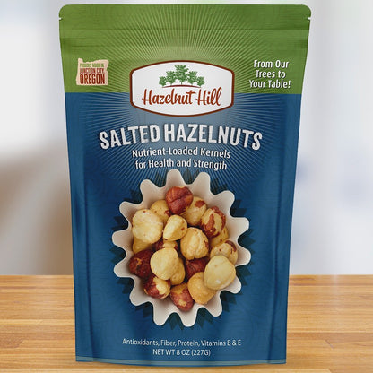 A package of Hazelnut Hill salted hazelnuts, with a picture of the hazelnuts on the front, indicating that they are roasted and salted. The package is labeled as vegan, gluten-free, and produced in Oregon.