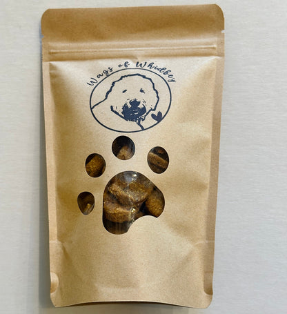 Kraft paper packaging with a paw print cut-out showing the treats inside, and a stamp of a dog with the words 'Wags of Whidbey'